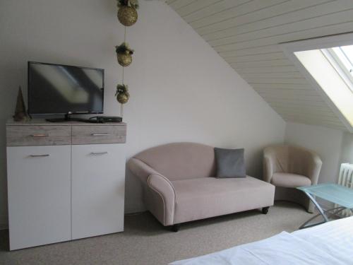 a living room with a tv and a chair at Hotel Skandinavia in Sankt Andreasberg