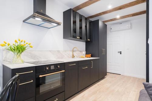 a kitchen with black cabinets and a sink at Miodowa Faktoria #7 by Rentoom in Toruń