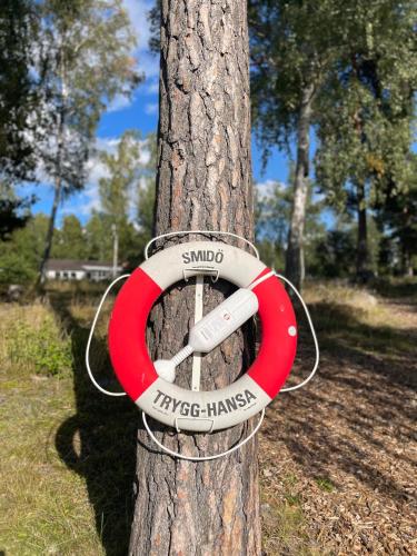 a red and white ring hanging on a tree at Relaxing Lake Oasis with Jacuzzi - Amazing view & Private Pier in Stockholm