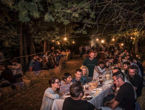 a group of people sitting at long tables at night at Malvarina in Capodacqua