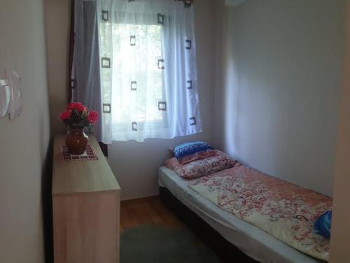 a small bedroom with a bed and a window at FÜGE-FA-HÁZ VÁSÁROSNAMÉNY - GERGELYIUGORNYA in Vásárosnamény