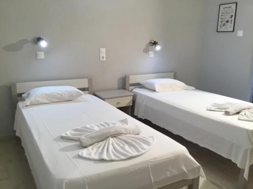 two beds in a room with white sheets and pillows at Plubis Studios in Kalamaki