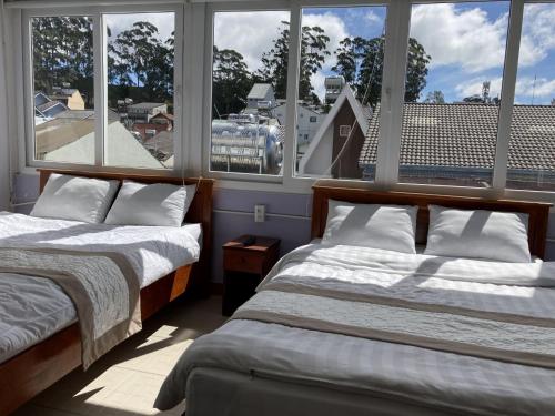 Duas camas num quarto com janelas grandes em Holly Hostel em Da Lat