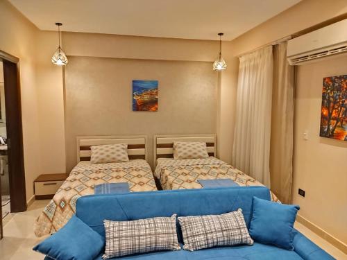 a bedroom with two beds and a blue couch at sherook993G2 in Madīnat ash Shurūq