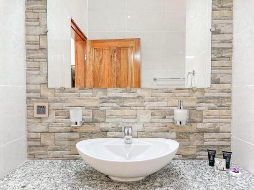 a bathroom with a white sink and a mirror at Palm Holiday Apartments in Grand'Anse Praslin