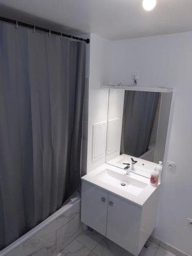 La salle de bains est pourvue d'un lavabo blanc et d'un miroir. dans l'établissement New Regence Apartment, à Serris