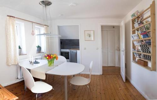 Feddersen's Ferienwohnung في هاريسلي: غرفة طعام بيضاء مع طاولة بيضاء وكراسي