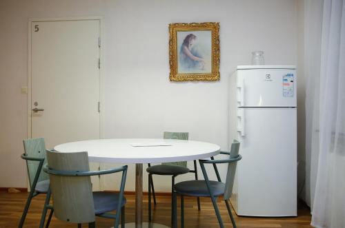 une table blanche avec des chaises et un réfrigérateur blanc dans l'établissement Motel Tornio, à Tornio