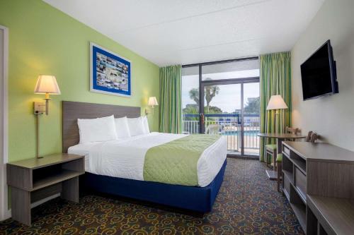 a hotel room with a bed and a balcony at Travelodge by Wyndham Outer Banks/Kill Devil Hills in Kill Devil Hills