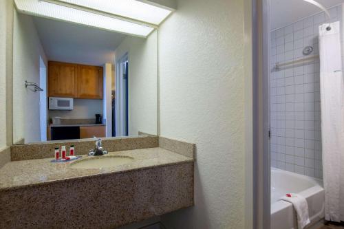 a bathroom with a sink and a mirror and a tub at Travelodge by Wyndham Outer Banks/Kill Devil Hills in Kill Devil Hills