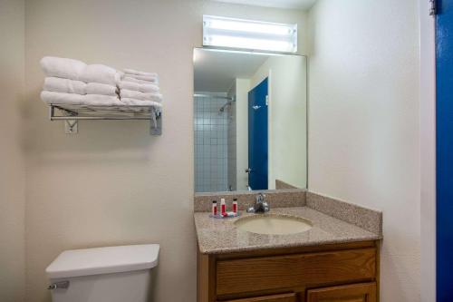 a bathroom with a sink and a mirror and a toilet at Travelodge by Wyndham Outer Banks/Kill Devil Hills in Kill Devil Hills