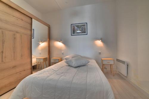 1 dormitorio con 1 cama con 2 mesas y espejo en Gite 8 personnes - La Ronçoise, en La Tremblade