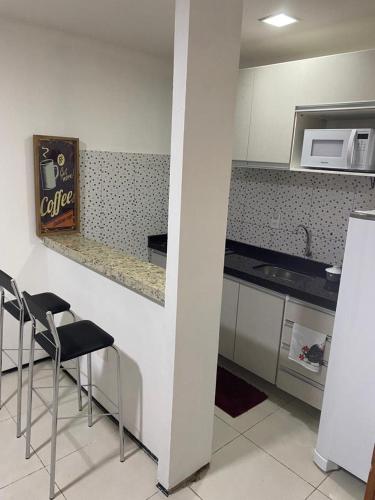 a kitchen with two chairs and a counter with a microwave at Pousada Residencial Milagre 01 in Juazeiro do Norte