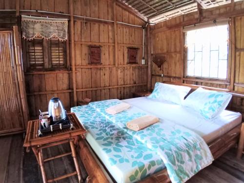 ein Schlafzimmer mit einem Bett und einem Nachttisch mit einem Tisch in der Unterkunft Mekong Delta Ricefield Lodge in Cần Thơ