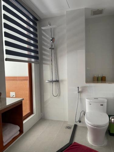 a bathroom with a shower and a toilet and a window at Four Oceans Beach Resort - Bon Bien Mui Ne in Mui Ne