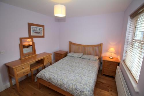 um quarto com uma cama, uma secretária e um espelho em SeaSpray Cottage em Rathmullan