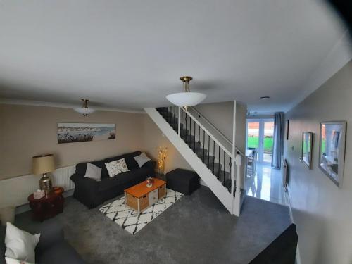 a living room with a couch and a staircase at Cosy 3 bedroom residential house, private garden, 30 minutes from Alton Towers, 5 minute walk to Trentham Gardens. in Stoke on Trent