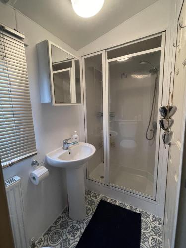 a white bathroom with a shower and a sink at The Retreat at The Inn in Spilsby