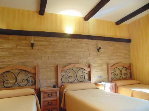 sypialnia z 2 łóżkami i ceglaną ścianą w obiekcie Hostal El 402 w mieście Iznalloz