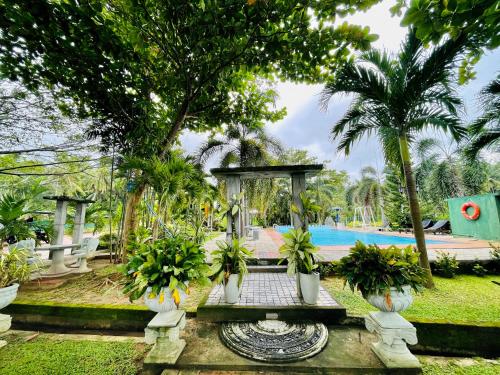 a garden with a fountain and a swimming pool at Tishan Holiday Resort in Polonnaruwa
