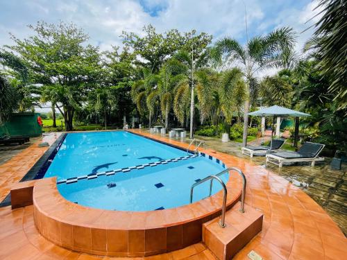 a large swimming pool with a wooden floor and trees at Tishan Holiday Resort in Polonnaruwa