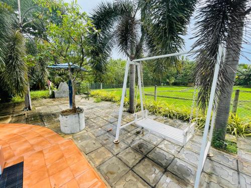 a swing in a garden with a palm tree at Tishan Holiday Resort in Polonnaruwa