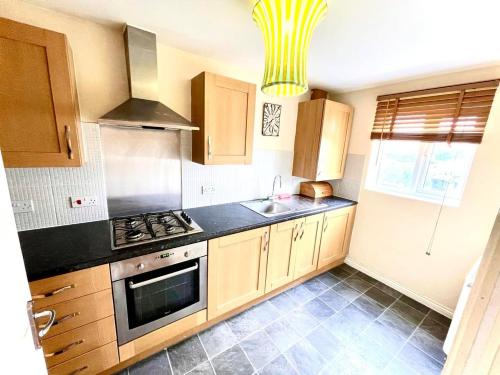a kitchen with wooden cabinets and a stove top oven at Lakeside Stylish 3 Bedroom House in Grays Thurrock
