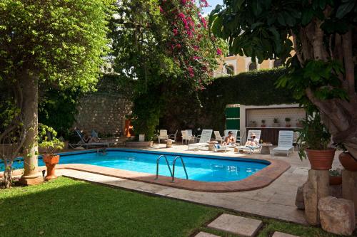 a swimming pool in a yard with people sitting around it at Casa del Balam Merida in Mérida