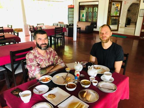 two men sitting at a table eating food at Tishan Holiday Resort in Polonnaruwa