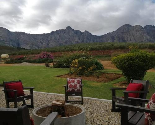 a group of chairs sitting on a patio with mountains in the background at Vredehoek Guest Farm in Breerivier