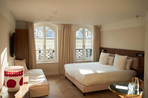 a bedroom with a large bed and two windows at Hôtel du Sentier in Paris