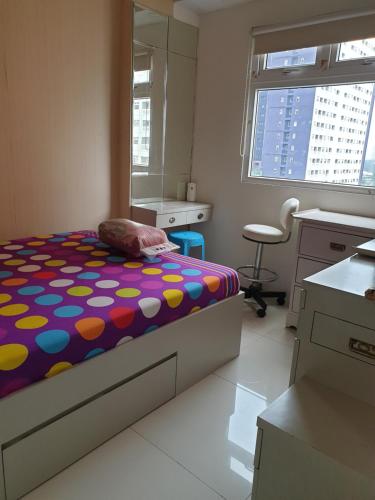 a bedroom with a bed and a desk and a chair at Properti9 at Apartemen Green Pramuka in Jakarta