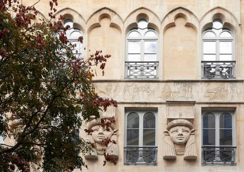 two heads on the side of a building with windows at Hôtel du Sentier in Paris