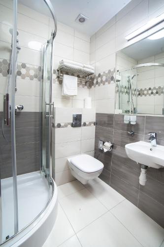 a bathroom with a toilet and a sink and a shower at Hotel Dworek Wapionka in Górzno
