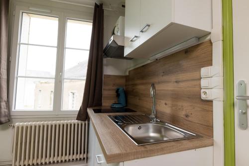 une petite cuisine avec un évier et une fenêtre dans l'établissement La Savane - Dormir Comme à la maison -, à Châteaubriant