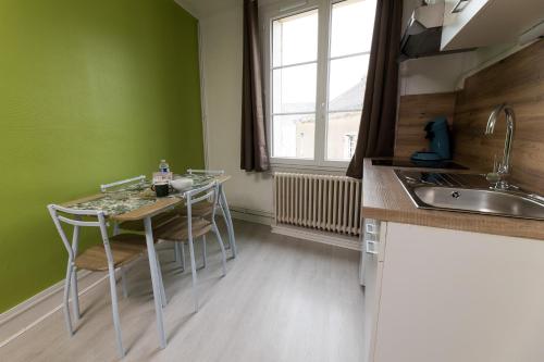 une cuisine avec une table, des chaises et un évier dans l'établissement La Savane - Dormir Comme à la maison -, à Châteaubriant