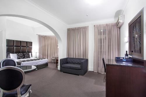 a hotel room with a bed and a couch and a chair at Mercure Maitland Monte Pio in Maitland