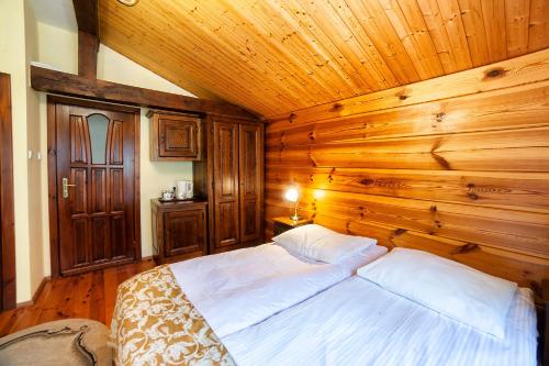 a bedroom with a bed in a wooden wall at Hotel Dworek Wapionka in Górzno