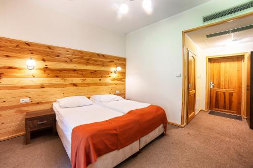 a bedroom with a large bed and a wooden wall at Hotel Dworek Wapionka in Górzno