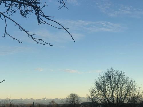 a blue sky with trees and mountains in the background at Ferienwohnung Design & Natur in Fronreute