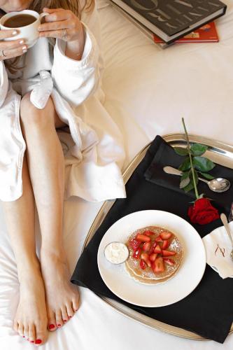 a woman sitting on a bed with a plate of food at Hotel ZaZa Houston Memorial City in Houston