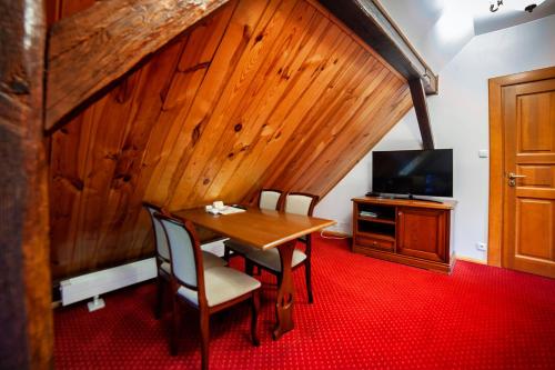 a dining room with a table and a television at Hotel Dworek Wapionka in Górzno
