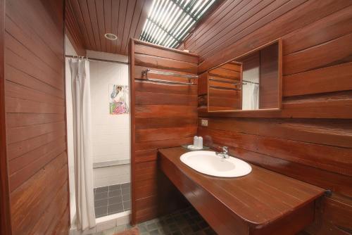 ein Badezimmer mit Holzwänden, einem Waschbecken und einem Spiegel in der Unterkunft Sans Souci Samui - SHA Plus in Chaweng