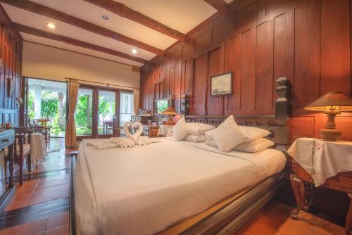 ein großes Bett in einem Zimmer mit Holzwänden in der Unterkunft Sans Souci Samui - SHA Plus in Chaweng