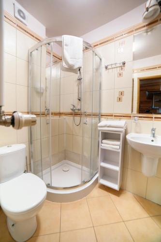 a bathroom with a shower and a toilet and a sink at Hotel Dworek Wapionka in Górzno