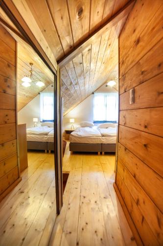 a large room with two beds and wooden walls at Hotel Dworek Wapionka in Górzno