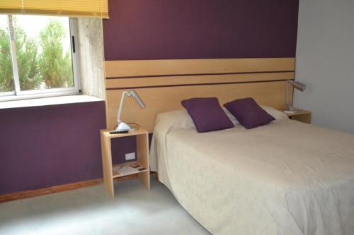 1 dormitorio con 2 camas, paredes de color púrpura y ventana en Cañas Suites Urbanas en Mina Clavero