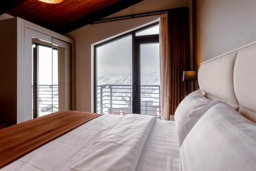 a bedroom with a bed and a large window at Hotel Tsiga in Gudauri