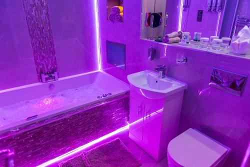 a pink bathroom with a tub and a toilet and a sink at Meridian Serviced Apartments in Bradford