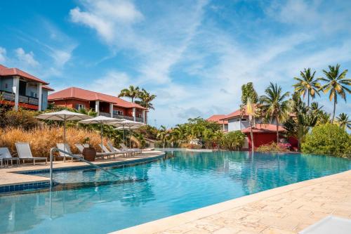 - une piscine dans un complexe avec des chaises et des palmiers dans l'établissement Les Villas du Lagon, au François